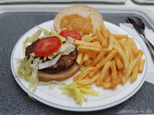 Veganer Umami Burger (Gl) belegt mit Eisberg, Tomaten und Kräuter-Dip (1,Gl,Nu,Sf,So) im Burgerbrötchen (Gl,Se), dazu Pommes frites und einen Beilagensalat nach Wahl