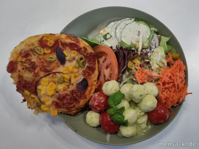 Bowl mit Blattsalat, Karotten, Mais, Tomaten, Karottensalat (Gl,Nu,Sf), Weißkrautsalat (1,5,Gl,Nu,Sw,Sl,Sf), Rote Bete-Salat (1,5,Sw), hausgemachte Pizzazunge mit Oliven, Paprika und veganem Käse oder wahlweise mit Käse (1,Gl), als Topping Mozzarella mit Tomaten und Rucolapesto (5,La,Sw), dazu Kräuterdressing (5,Gl,Nu,Sw,Sf)