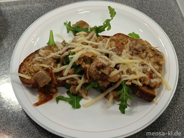 Sauerteigbrot belegt mit Pilzen, Gruyére, Rucola, getrockneten Tomaten und Pinienkernen (La,Sl,Sf) und Karottensalat (1,5,La,Sw)