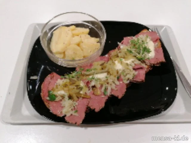 Geröstetes Dinkelbrot belegt (Gl) mit Pastrami (geräuchertes Rindfleisch), Krautsalat, Kräuterquark, Gewürzgurke und Honig-Senf-Soße (1,5,9,La,Sw,Sf,R), dazu klarer Kartoffelsalat (5,Sw)