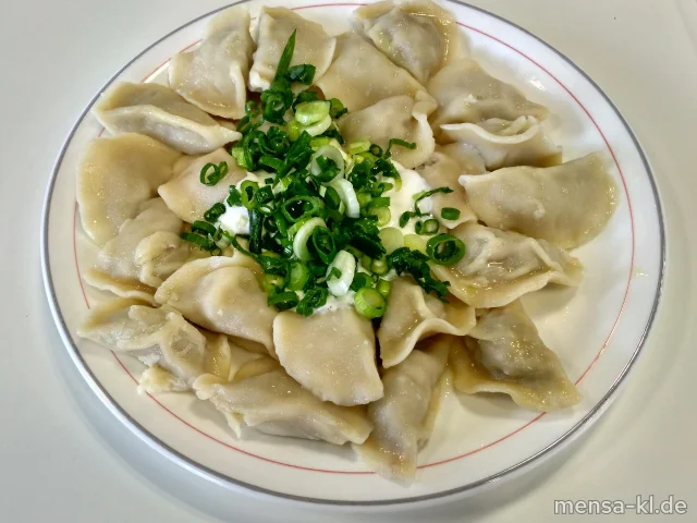 "Pelmeni": Teigtaschen mit Schweinefleischfüllung (1,Gl,Ei,La,Sl,S), dazu Saure Sahne-Dip (La), Frühlingszwiebeln (1,3,Ei,La) und Salat