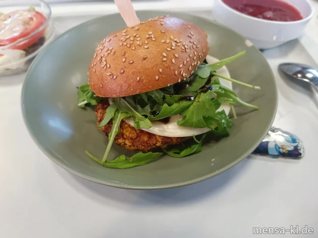 Campus Chicken Burger: Crispy Chicken (Gl,Sl,G) belegt mit Mozzarella, Rucola, Balsamico (La) und Kräuterfrischkäse (La) im Burger Bun (Gl,La), dazu Salat