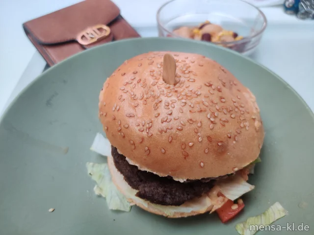 Campus Chili Cheese Burger: BIO-Rindfleisch (Ei,R) belegt mit Tomaten, Eisberg und scharfe Jalapenos (1,Gl,La) im Brioche Burger Bun (Gl,La), dazu Bohnensalat (1,5,La,Sw)