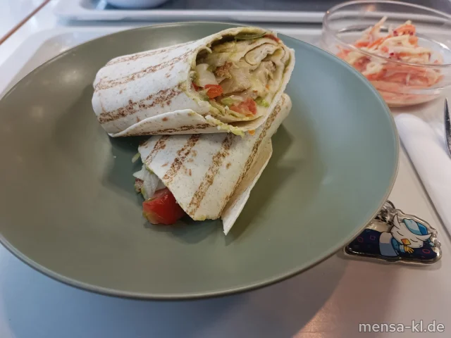 Wrap gefüllt mit Hähnchenstreifen, Eisberg, Tomaten, Guacamole und Gouda (1,Gl,La,Sl,So,R,G), dazu Guacamole-Dip (La) und Salat (1,5,Sw)