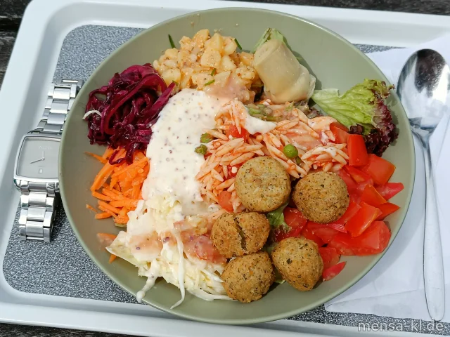 Bowl mit Blattsalat, Artischocke, Gurkensalat (1,5,Sw,Sf), Karottensalat (Gl,Nu,Sf), Rotkohlsalat (3,Nu), Krautsalat (1,5,Gl,Nu,Sw,Sl,Sf), Kartoffelsalat (Gl,Nu,Sf) und Falafelbällchen (1,Gl,Sl), dazu ein Senf-Dressing (Gl,Nu,Sf)